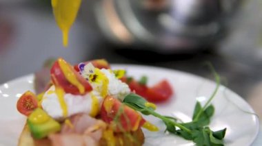 Benedict usulü yumurta. Yumurtalı sandviçin üzerinde yenilebilir çiçekler, haşlanmış yumurtalar, üzerine sos serpiştirilmiş Benedict.