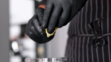 Forseps limonlu su bardağını yakın plan çeker. Makro yavaş çekimde meyve dilimli soğuk su. Yaz içeceği, kıskaçlar ve bar ekipmanlarıyla hazırlandı. Kokteyl süreci konsepti yapılıyor