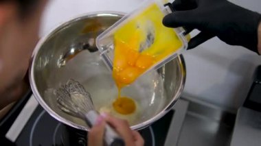 Hollandaise soslu Benedict usulü yumurta. Hollandaise sosunu metal bir kaşıkla güveçte harmanlamak.