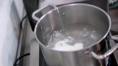 Haşlanmış yumurta kaynatın. Bir tencerede kaynayan suda haşlanmış yumurta. Yakın plan. Haşlanmış yumurta bir tencerede kaynatılır. Kavrulmuş bir yumurta ocakta düşük ısıda sıcak suda kaynatılır..