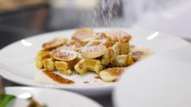 Karamelli ve şekerli Belçika waffle 'ları. Narin pudra şekeriyle süslenmiş kadife karamel dolgulu Belçika waffle 'ı. Çürük, haşlanmış yumurta Benedict sandviç tabağında.