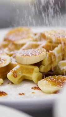 Karamelli ve şekerli Belçika waffle 'ları. Narin pudra şekeriyle süslenmiş kadife karamel dolgulu Belçika waffle 'ı. Çürük, haşlanmış yumurta Benedict sandviç tabağında.