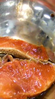 Izgara için cam bir tabakta somon bifteği marine etmek. Soğan, limon ve baharatla marine edilmiş somon..
