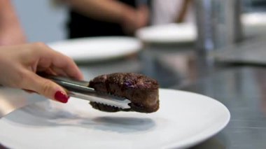 Kesme tahtasındaki büyük bir mutfak bıçağıyla bifteği kesme işlemi. Sulu sığır eti parçalara ayrıldı. Şefin elinin yakın çekimi, ağır çekim. 4k görüntü