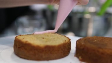 Şekerlemeler, pişirme ve pişirme konsepti. Evdeki mutfakta pasta yapan kadın. Bento keki yapma süreci. Elinde kremalı ahudududulu kek tutan kadın.