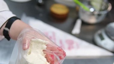 Şekerlemeler, pişirme ve pişirme konsepti. Evdeki mutfakta pasta yapan kadın. Bento keki yapma süreci. Elinde kremalı ahudududulu kek tutan kadın.