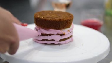 Şekerlemeler, pişirme ve pişirme konsepti. Evdeki mutfakta pasta yapan kadın. Bento keki yapma süreci. Elinde kremalı ahudududulu kek tutan kadın.