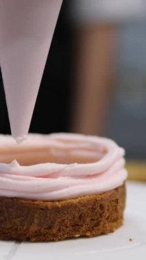 Şekerlemeler, pişirme ve pişirme konsepti. Evdeki mutfakta pasta yapan kadın. Bento keki yapma süreci. Elinde kremalı ahudududulu kek tutan kadın.