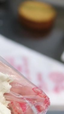 Şekerlemeler, pişirme ve pişirme konsepti. Evdeki mutfakta pasta yapan kadın. Bento keki yapma süreci. Elinde kremalı ahudududulu kek tutan kadın.