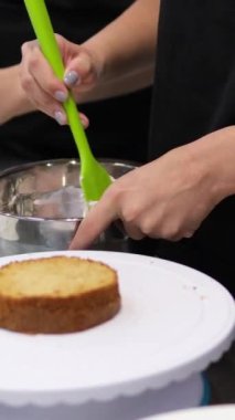 Şekerlemeler, pişirme ve pişirme konsepti. Evdeki mutfakta pasta yapan kadın. Bento keki yapma süreci. Elinde kremalı ahudududulu kek tutan kadın.