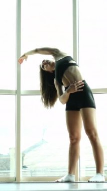 Hamile fitness koçu doğum öncesi yoga dersinde yan esneme gösterisi yapıyor. Kız yana doğru eğiliyor