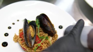 Paella geleneksel İspanyol yemekleri. İnsan kızartma tavasından tabağa deniz mahsulü paella koyar. Midyeli paella, Kral karidesleri, langoustine ve mürekkep balıklarıyla. Paella pişiren kişi. Akşam yemeği. 4K