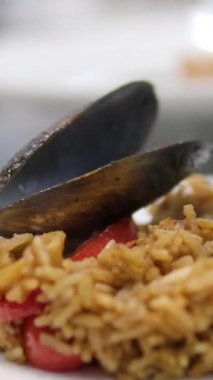 Paella geleneksel İspanyol yemekleri. İnsan kızartma tavasından tabağa deniz mahsulü paella koyar. Midyeli paella, Kral karidesleri, langoustine ve mürekkep balıklarıyla. Paella pişiren kişi. Akşam yemeği. 4K