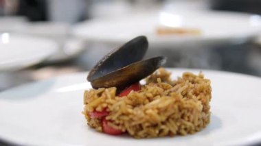 Paella geleneksel İspanyol yemekleri. İnsan kızartma tavasından tabağa deniz mahsulü paella koyar. Midyeli paella, Kral karidesleri, langoustine ve mürekkep balıklarıyla. Paella pişiren kişi. Akşam yemeği. 4K