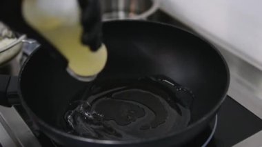 Aşçı tavaya sebze yağı döker.