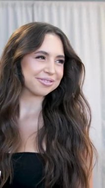 Beyaz tenli esmer kız gülümsüyor. Teşekkürler. Salonda dolaşmak için geri dönen telefonlara teşekkür ediyor. Diş teli takan kız, gülümseyen telefon. Kız bir şey unuttu ve geri döndü.