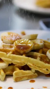 Beyaz üzerine muz, krema ve karamel soslu lezzetli Belçika waffleları.