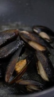 Large green mussels in shells on tray with ice. Black background. Top view. Copy space.