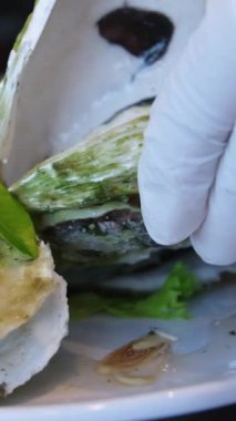 İstiridye yiyen kişi yakından. Limonlu buzlu istiridye. Restoranda koca tabakta taze istiridye yiyen adam. Servis masası. İstiridye