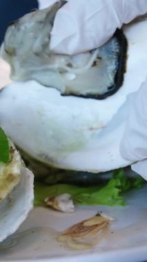 İstiridye yiyen kişi yakından. Limonlu buzlu istiridye. Restoranda koca tabakta taze istiridye yiyen adam. Servis masası. İstiridye