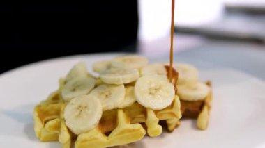 Beyaz üzerine muz, krema ve karamel soslu lezzetli Belçika waffleları.