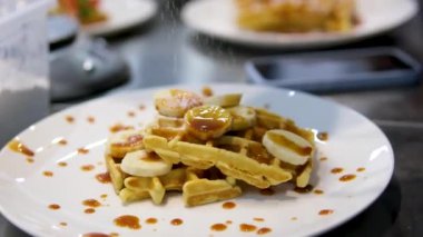 Beyaz üzerine muz, krema ve karamel soslu lezzetli Belçika waffleları.