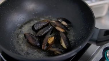 Large green mussels in shells on tray with ice. Black background. Top view. Copy space.