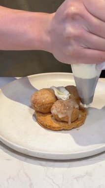 Pasta şefi bisküvi turtasını pasta poşetinden çıkan kremayla dekore ediyor. Ticari fırında boru torbasıyla pasta hazırlığı. Pastayı süslemek için.