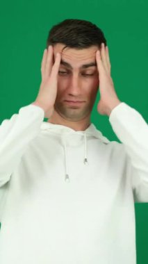 Yeşil arka plandaki yakışıklı adamın beyin patlaması duyguları. Koyu renk, yakın plan, genç adam.