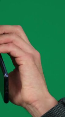 Yeşil arka plandaki yakışıklı bir adamın ciddi telefon konuşmaları. Koyu renk saçlı genç adam. Elden konuşma, SMS 'i ara, internetten arama cihazı, patronun iş ilanı.