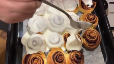 Round homemade baked cinnabons with white icing on top, close up view. Homemade buns.