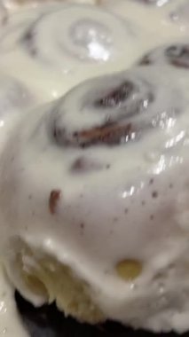 Round homemade baked cinnabons with white icing on top, close up view. Homemade buns.