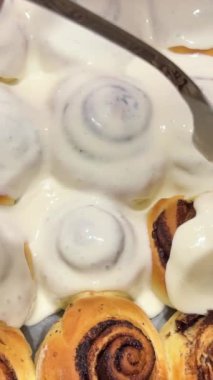 Round homemade baked cinnabons with white icing on top, close up view. Homemade buns.