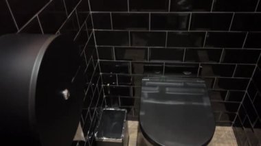 Siyah bir tuvalet siyah kiremit duvarlı bir banyoda. Siyah kiremitli tuvalet.