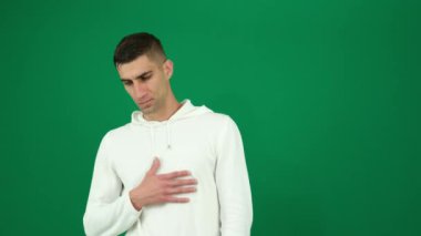 Yeşil arka plandaki yakışıklı adamın kalbinde anksiyete acısını hisset. Koyu renk saçlı, genç adam.
