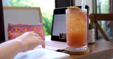 İnternetteki kız tableti. Çevrimiçi çalışma konferansı iletişimi bir kafede oturur. Meyve suyu içen bir kız. Mutlu genç kadın evinde rahat bir koltukta rahatlayıp tablete mesaj atıyor.