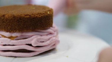 Şekerlemeler, pişirme ve pişirme konsepti. Evdeki mutfakta pasta yapan kadın. Bento keki yapma süreci. Elinde kremalı ahudududulu kek tutan kadın.