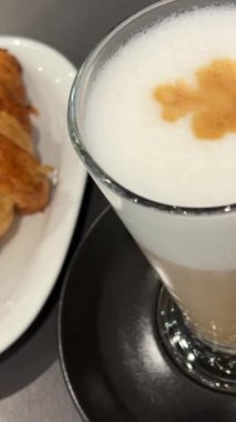 Kruvasan ve latte. Taze iştah açıcı kruvasanlar ve ahşap arka planda kahve, lezzetli kahvaltı kavramı.