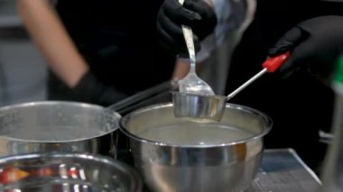 Limon kabuğuyla doldurulmuş alkolü süzer ve süzer. Ana, şeker şurubuyla karıştırmak için gereken sıvı hacmini ölçer. Krema süzgecinden geçerek yaşa. Turunçgiller süt altında soyulur.