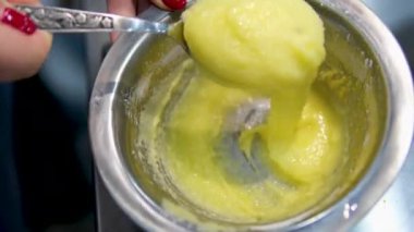 Ahşap kaşık, beyaz seramik kasede kremalı krema karıştırıyor. Evde ya da restoranda yemek hazırlamak için kremalı tatlı karışımı. muhallebi yap