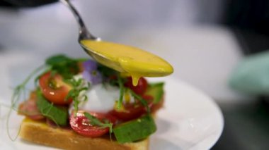 Lezzetli yumurtalı benedikt, iştah açıcı ve besleyici bir kahvaltı için beyaz tabakta servis edilir.
