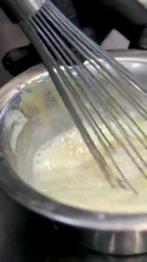 Ahşap kaşık, beyaz seramik kasede kremalı krema karıştırıyor. Evde ya da restoranda yemek hazırlamak için kremalı tatlı karışımı. muhallebi yap