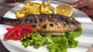 Limonlu beyaz tabak. Güzel sunum. Kameranın önünde kıvrılıyor. Salata balığı Dorado kızartması.