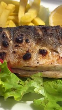 Limonlu beyaz tabak. Güzel sunum. Kameranın önünde kıvrılıyor. Salata balığı Dorado kızartması.