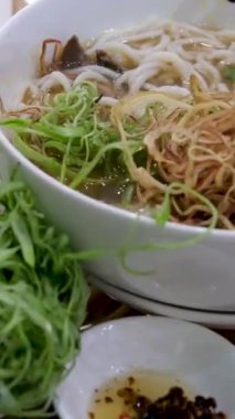 Vietnamlı çorbacı kızların elleri çubuklu pilav eriştelerini alıyor ve geleneksel lezzetli yemekler yiyorlar. Geleneksel Vietnam et çorbası.