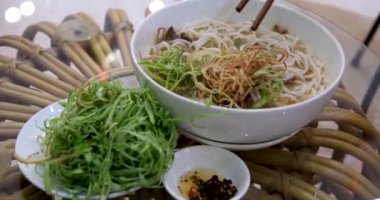 Vietnamlı çorbacı kızların elleri çubuklu pilav eriştelerini alıyor ve geleneksel lezzetli yemekler yiyorlar. Geleneksel Vietnam et çorbası.