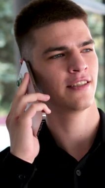 Siyah saçlı ve mavi gözlü yakışıklı bir adam. Melez ırk uyruğu. Ofisin yakınında telefonla konuşan bir adam.