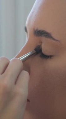 Kadının gözü açık, yakın çekim. Kaşlar ve kirpikler için göz makyajı. Göz farı ve toz fırçası yanında. makyaj boyası gözler