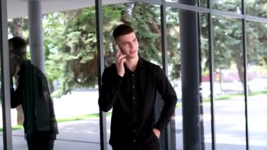 Sokakta kahve ve akıllı telefonlu şık bir gencin portresi. Siyah saçlı, mavi gözlü yakışıklı bir adam. Melez ırk uyruğu. Adam telefonda konuşuyor.
