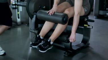 Genç, mutlu, güler yüzlü, sportif kadın spor kulaklıklı, beyaz spor kulaklıklı, müzik ısınma egzersizlerini dinleyen iç mekanda spor motivasyonu yaşam tarzında bacak çalıştıran spor eğitmeni. 